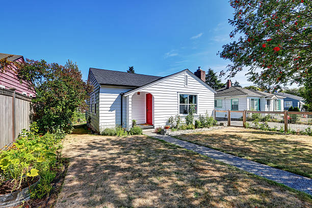 istock Small white rambler house with red front door. 595343788