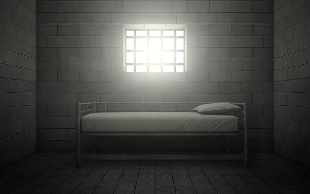 Prison cell with light shining through a barred window stock photo