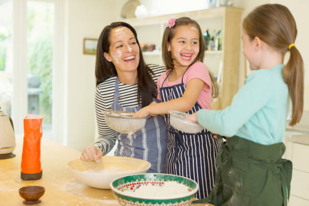 istock Laughing mother and daughters baking with flour on faces in kitchen 595348003