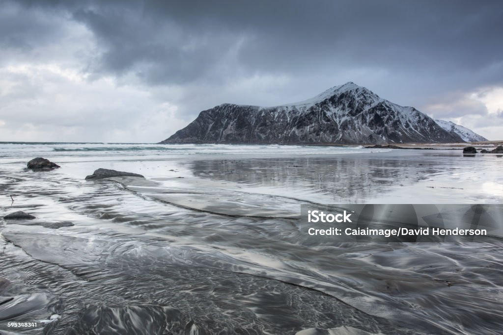 Snow covered rock formation on cold ocean beach, Skagsanden Beach, Lofoten Islands, Norway  Norway Stock Photo