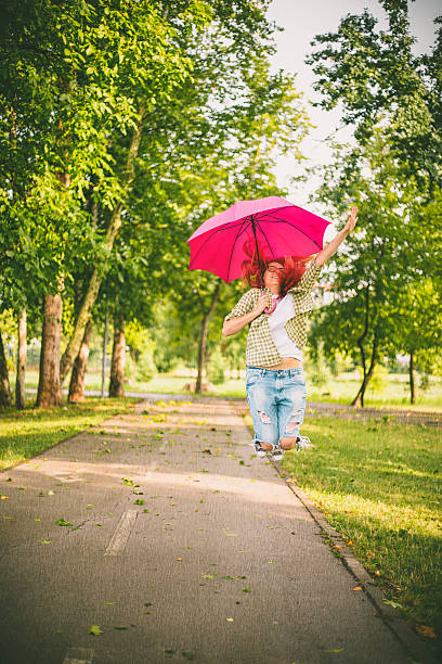 istock happy young woman jumping with umbrella 595349512