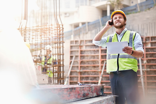 Portrait of confident male building contractor holding blueprint at construction site