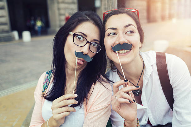Stache-on-a-stick awareness and fun Girls putting fake staches for sympathy and awareness women movember mustache facial hair stock pictures, royalty-free photos & images