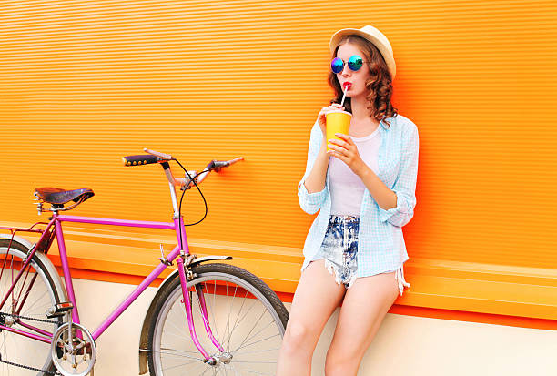 istock Fashion woman drinks fruit juice from cup with retro bicycle 595353642