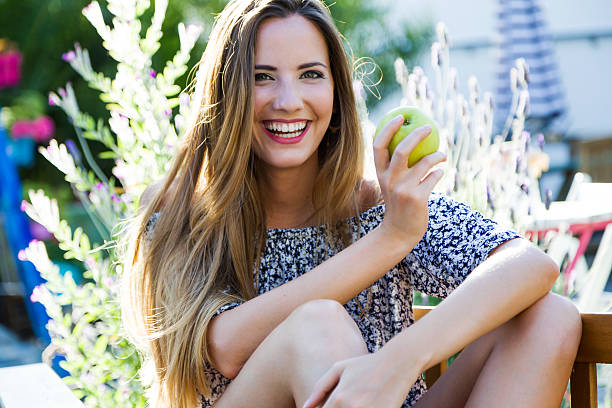 красивая молодая женщина ест яблоко в домашнем саду. - apple women green eating стоковые фото и изображения