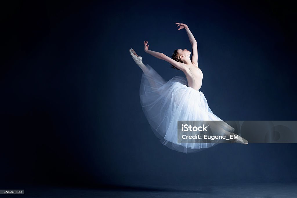 Young ballerina is dancing in a dark photostudio Young ballerina in a beautiful dress is dancing in a dark photostudio Ballet Stock Photo