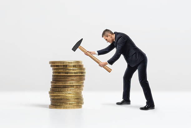 istock Side view of businessman crashing big golden coins stack with 595361868