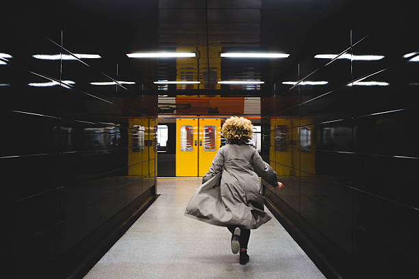 I missed the train! Rear view of businesswoman running to catch the subway train, which is already leaving the underground station. london england rush hour underground train stock pictures, royalty-free photos & images
