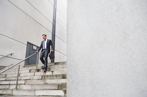 Businessman on his way to work. He is dressed in a formal suit and is walking down some steps.