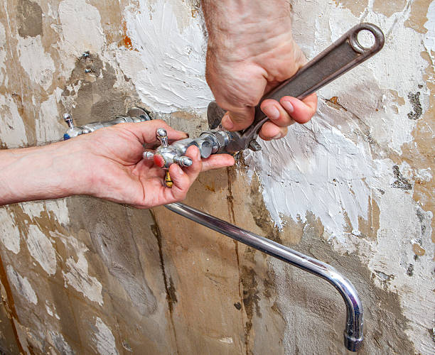 istock Hands plumber with an adjustable wrench, nut unscrewed flowing tap. 595365436