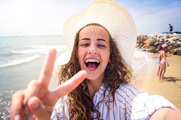 Beautiful woman on beach, laughing, taking selfie, sunny day