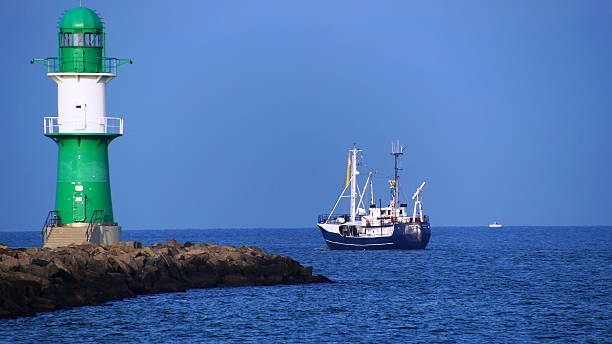 istock Boat Sailing On Sea By Lighthouse Against Clear Blue Sky 595366477