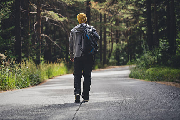 istock Male traveler with backpack walks forward by the road 595728004