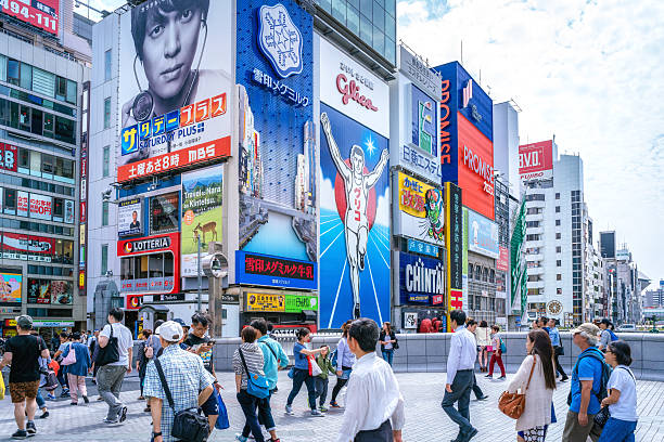 Dotonbori district, Osaka, Japan Tourists and locals walk below the famed advertisements lining Dotonbori Canal at. The district is one of Osaka's primary tourist destinations. osaka prefecture stock pictures, royalty-free photos & images