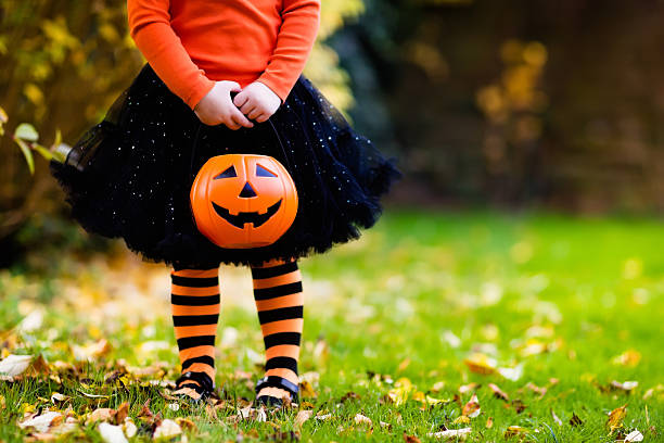 Little girl having fun on Halloween trick or treat Little girl in witch costume playing in autumn park. Child having fun at Halloween trick or treat. Kids trick or treating. Toddler kid with jack-o-lantern. Children with candy bucket in fall forest. trick or treat photos stock pictures, royalty-free photos & images