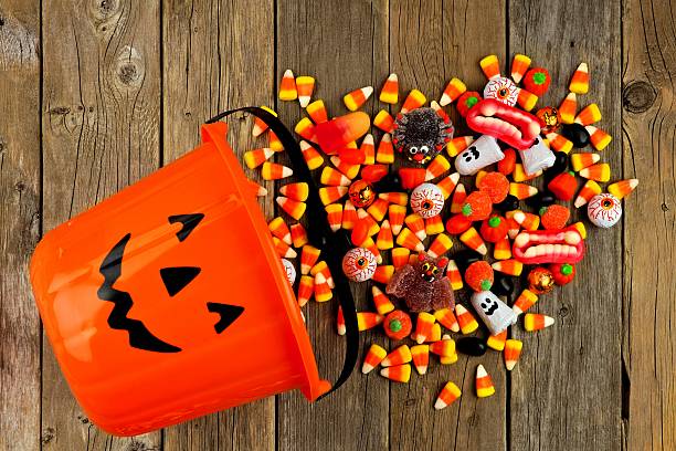 istock Halloween Jack o Lantern pail with spilling candy over wood 595734310
