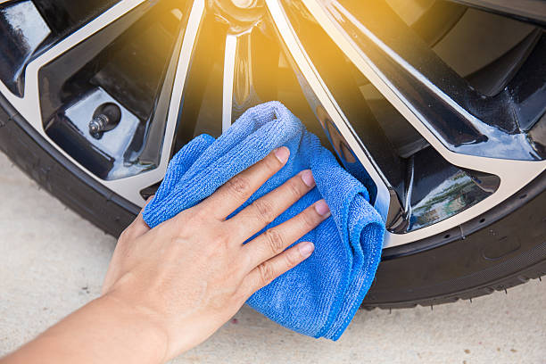 istock Hand with blue microfiber cloth cleaning car wheel. 595737382