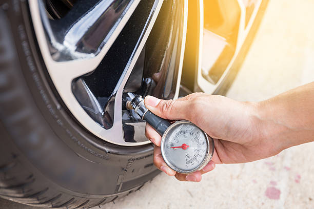 close-up of hand holding pressure gauge for car tyre pressure - compressed imagens e fotografias de stock