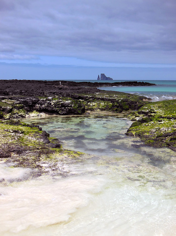 View along the shore with Kicker Rock in the distance off San Cristobal Island, Galapagos, Ecuador.