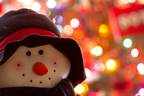 A snowman with a sign of happy holidays with christmas tree behind