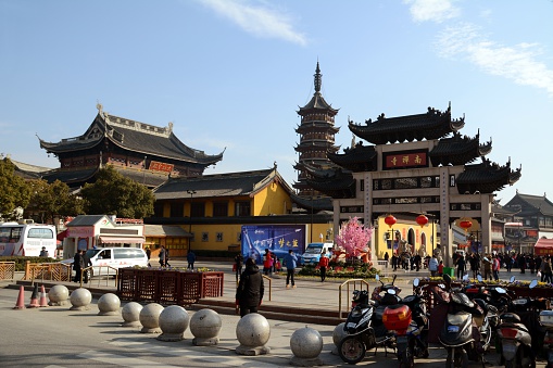 Wuxi, China - February 10, 2016: The Nanchan Temple, a landamrk of Wuxi, built during the Southern Dynasty (549 A.D.) and originally called Huguo Temple. People walking outside the temple, on the pedestrian street. Jiangsu province.
