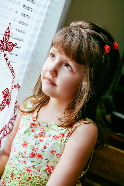 istock Sad little girl looking at window 595755642