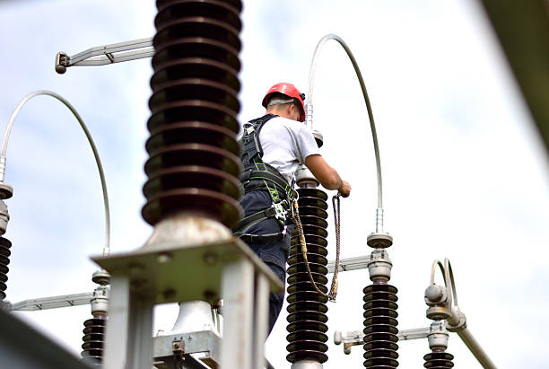 electrician with protective workwear, hardhat and safety harness working - power line electricity construction fuel and power generation imagens e fotografias de stock