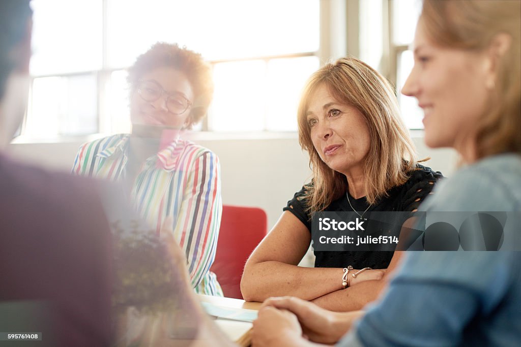 Unposed group of creative business people in an open concept Candid picture of a female boss and business team collaborating. Filtered serie with light flares, bokeh, warm sunny tones. Group Of People Stock Photo