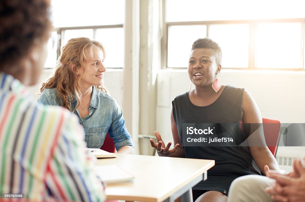 Unposed group of creative business people in an open concept Candid picture of a business team collaborating. Filtered serie with light flares, bokeh  and warm sunny tones. Women Stock Photo