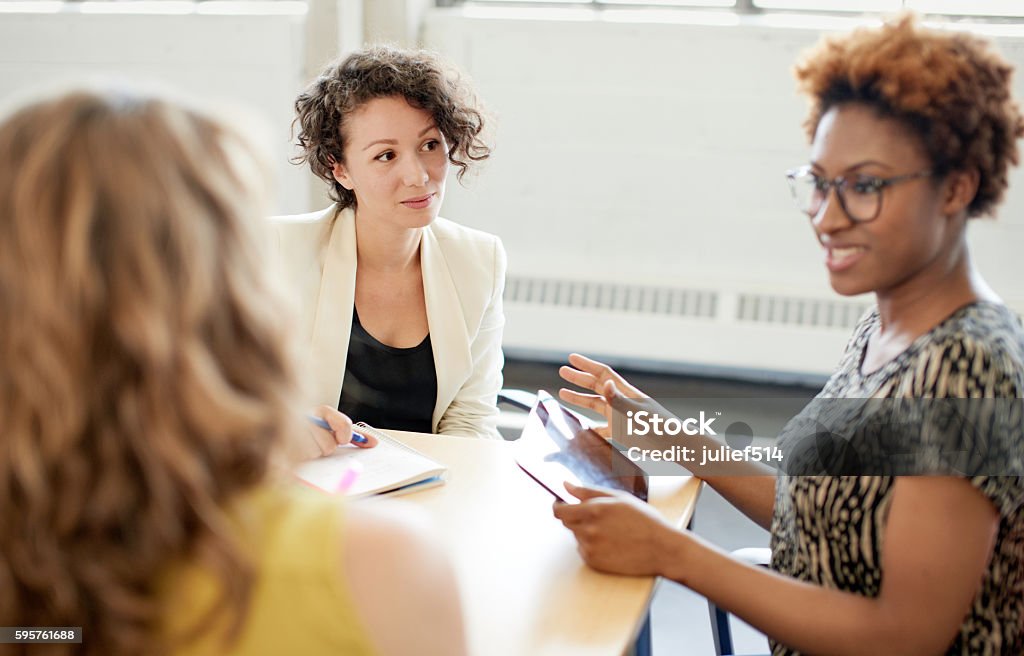 Unposed group of creative business people in an open concept Candid picture of a female boss and business team collaborating. Filtered serie with light flares, bokeh, warm sunny tones. Meeting Stock Photo