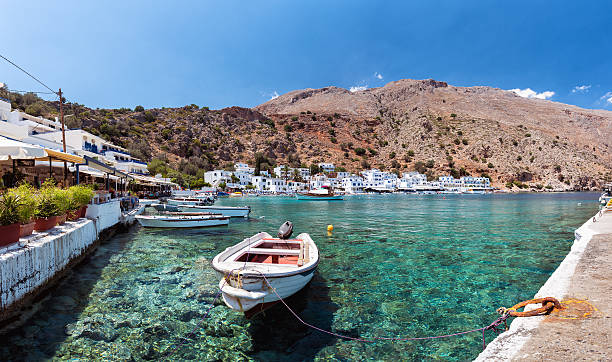 piccolo motoscafo nella baia d'acqua limpida sull'isola di creta - clear sky residential district house sky foto e immagini stock