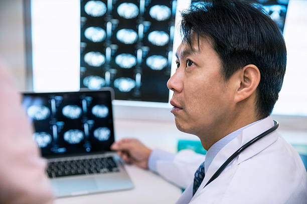 concentrated male doctor with patient examining mris in hospital - radiologist x ray computer medical scan imagens e fotografias de stock