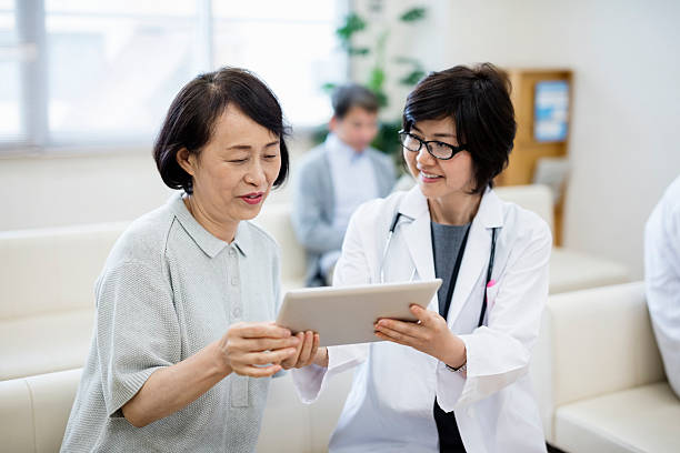 病院の患者にデジタルタブレットを示す女性医師 - asian ethnicity doctor patient healthcare and medicine ストックフォトと画像