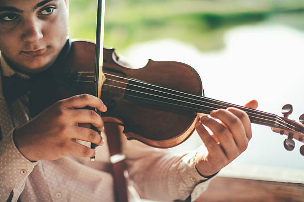 istock Playing violin by the lake 595763572