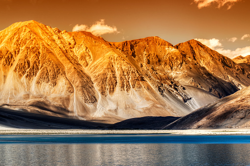 Beautiful Mountains and Pangong tso (Lake) in sun set. A huge lake in Ladakh, extends from India to Tibet. Leh, Ladakh, Jammu and Kashmir, India. Himalayan mountains in background. Colourful image.