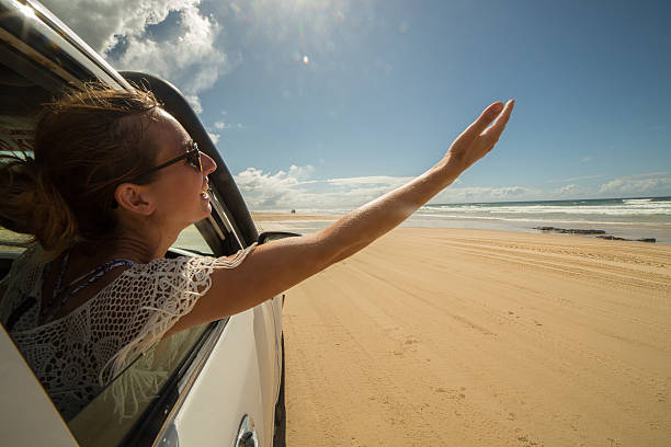 istock Young woman in a car driving on sandy beach 596041470