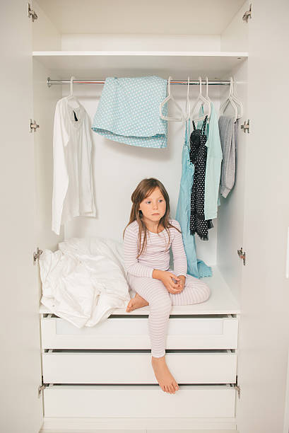 istock Sad little girl sitting in wardrobe 596046688