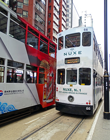 North Point, Hong Kong - February 10, 2016: Two old double-decker trams encounter while driving through North Point, Hong Kong. Both trams are covered with advertising. The tram in the north of the Hong Kong Island was established in 1904. The only double-decker cars modeled after the Blackpool Tramway are a tourist attraction.