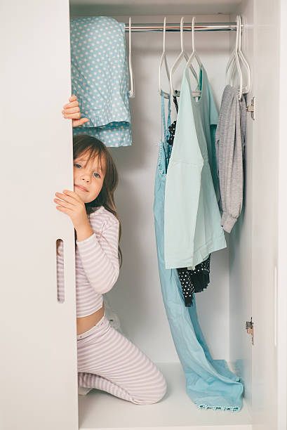 istock Cute little girl hiding in wardrobe 596048420