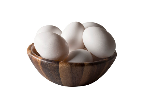 A wooden bowl with white chicken eggs isolated on white.