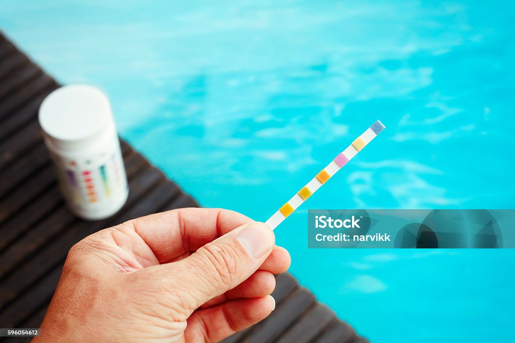 Checking water quality in the swimming pool Person checking water quality with test strip in the swimming pool (chlorine, ph, hardness, alkalinity) Swimming Pool Stock Photo