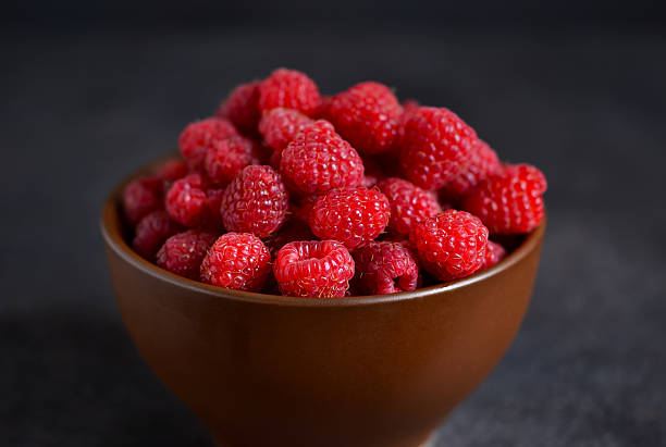 istock Fresh, juicy raspberries in a bowl on a black background 596055180
