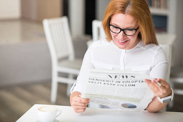 istock Joyful woman reading newspaper 596056994