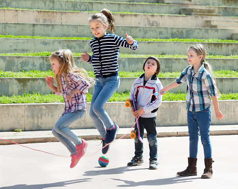 Young girl jumping while jump rope game with friends outdoor