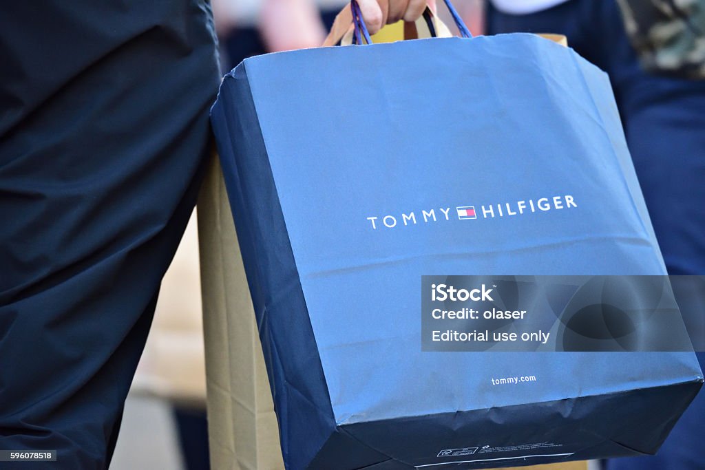 Person Walking On Sidewalk With Tommy Hilfiger Shopping Bag Stock