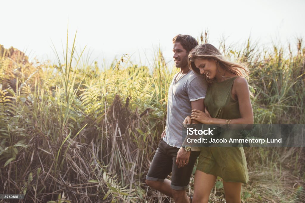 Romantic young couple walking together in countryside Outdoor shot of romantic young couple walking together in countryside. Young man and woman on a holiday. Walking Stock Photo