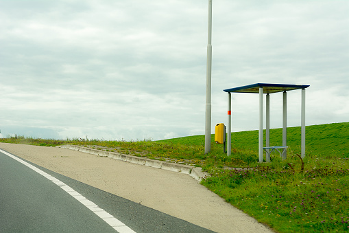 Busstop in Netherlands most rural empty province Friesland  made of steel joined bye a yellow wastebasket