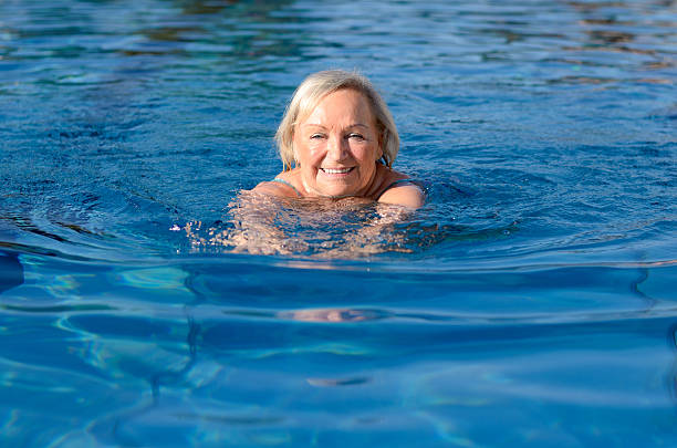 mujer anciana activa feliz sonriente - braza fotografías e imágenes de stock