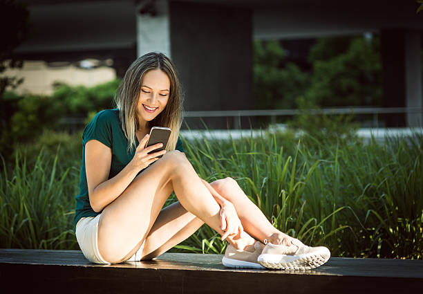 istock Beautiful young woman in real life using smartphone 596085426