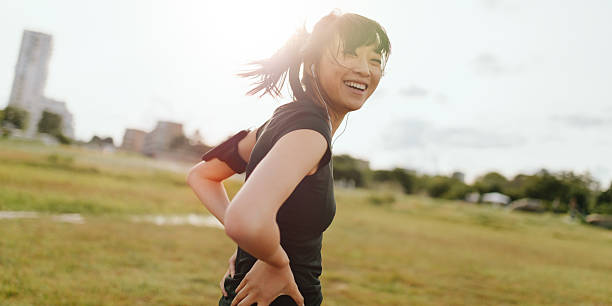 runner donna che ride in campo al mattino - running jogging asian ethnicity women foto e immagini stock